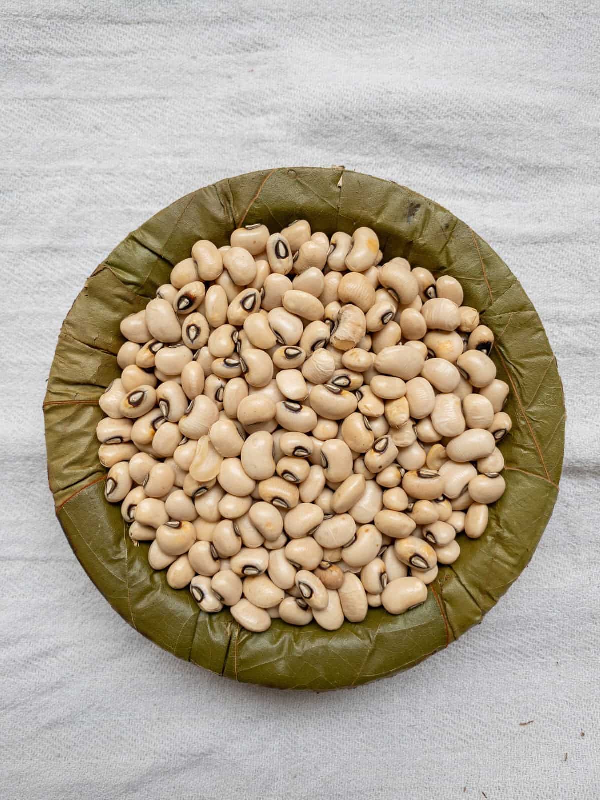 Black-eyed peas in a leaf bowl on a white cloth.