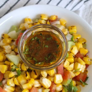 Grilled corn salad with cucumber, tomato, onion, coriander, and a bowl of chaat masala lemon dressing.