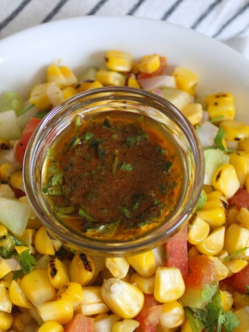 Grilled corn salad with cucumber, tomato, onion, coriander, and a bowl of chaat masala lemon dressing.