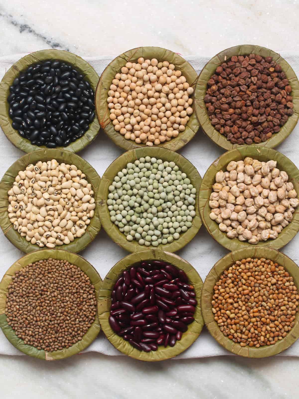 A collection of dried Indian beans and legumes arranged in leaf bowls.