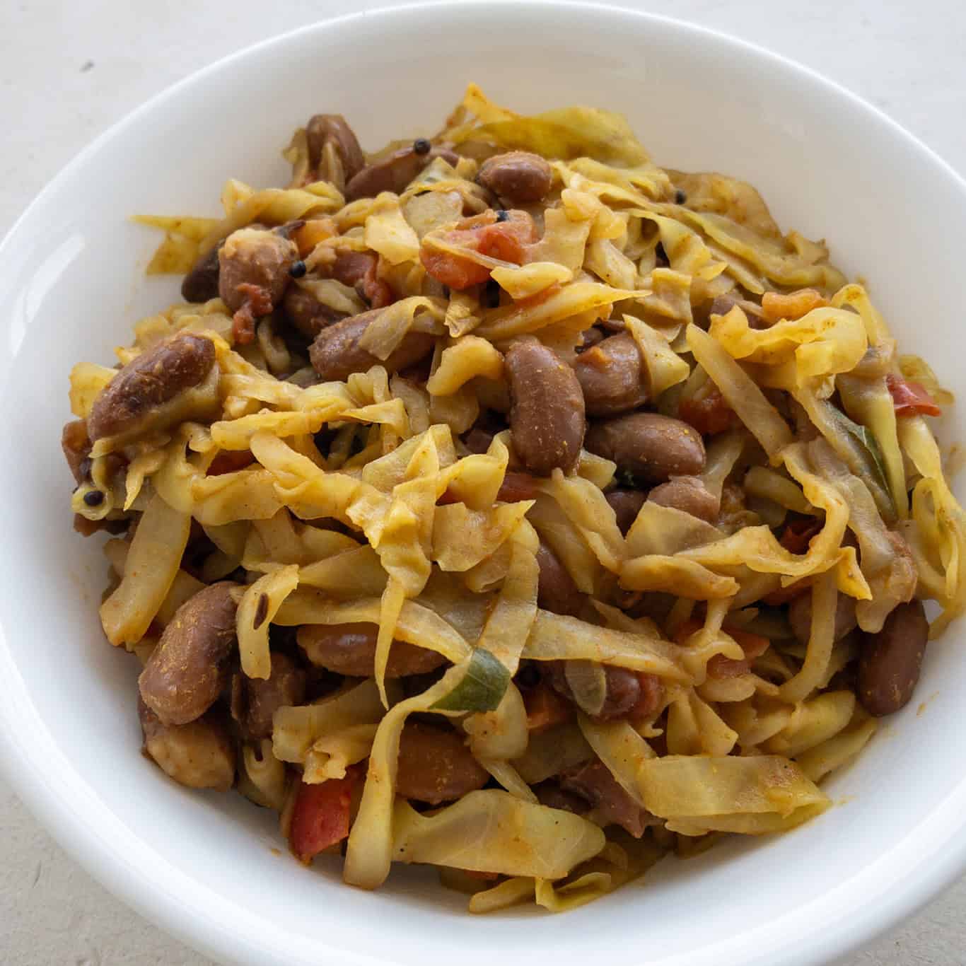 Finished Indian cabbage stir fry with kidney beans served in a white bowl.