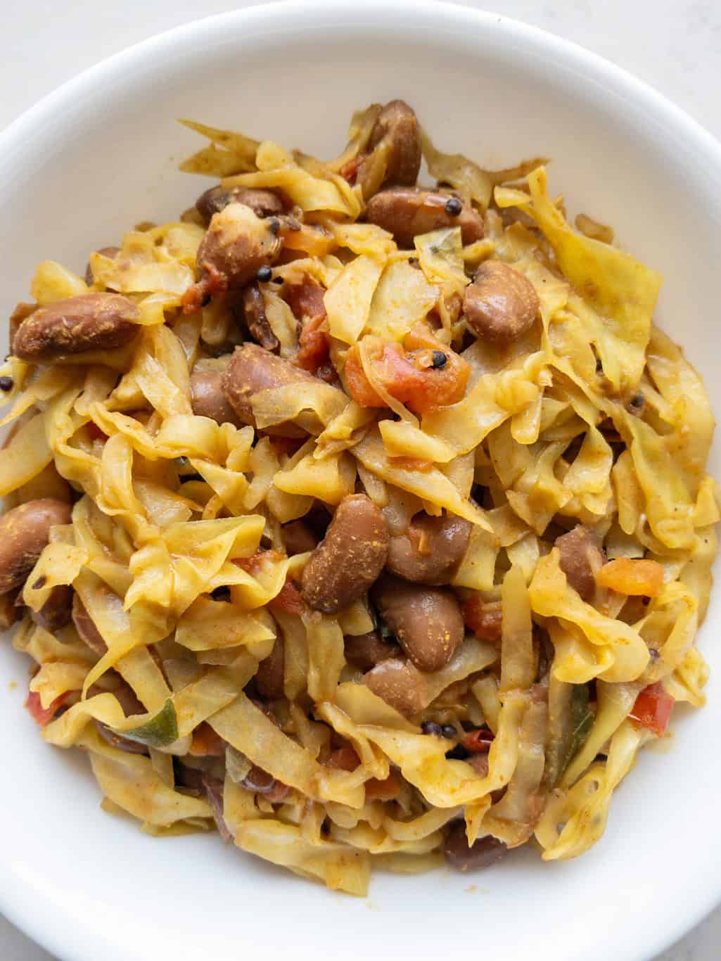 Close view of cabbage stir fry with kidney beans, tomatoes, and spices.