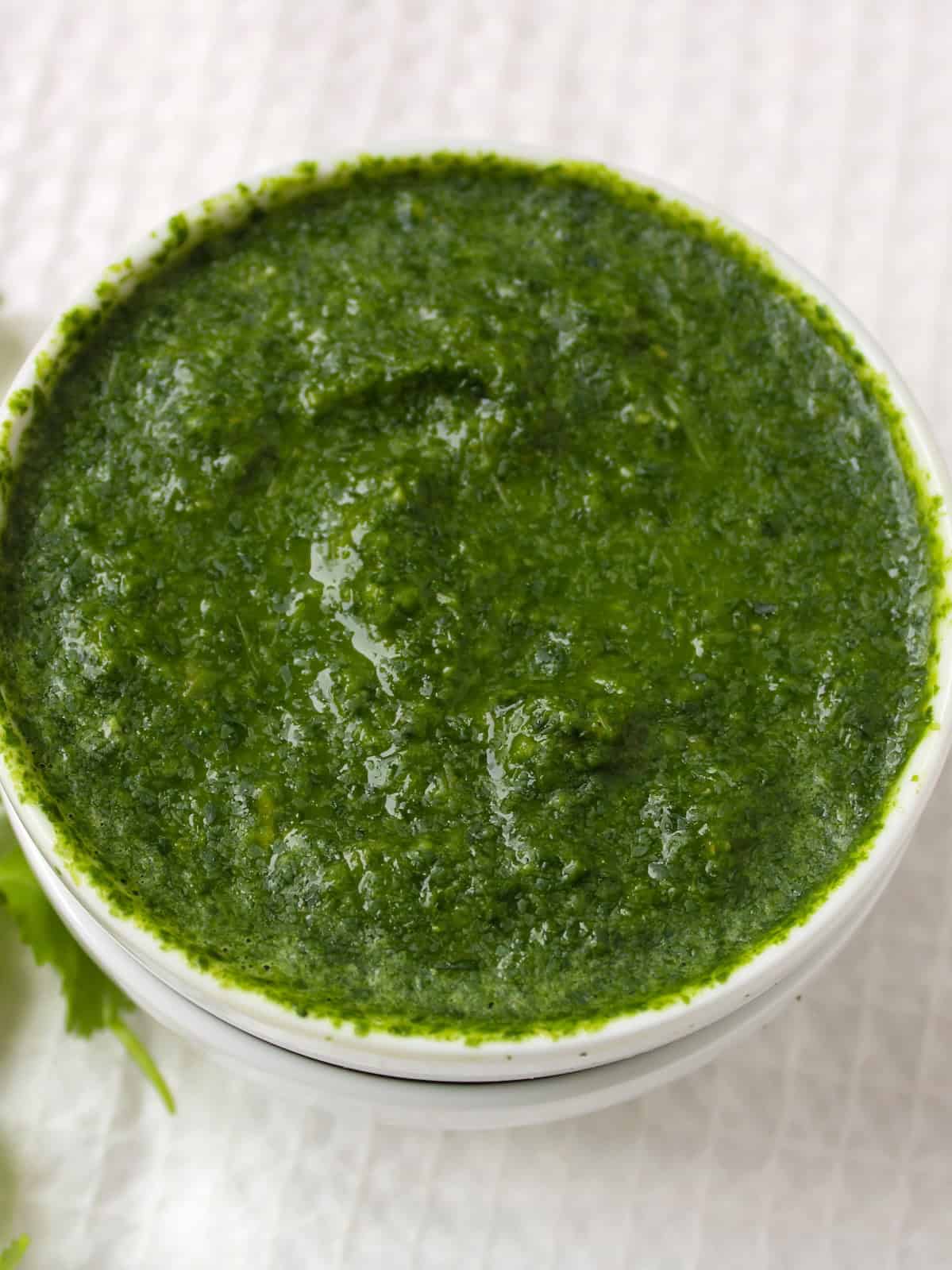 Close view of thick Indian green sauce in a small white serving bowl.