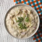 Finished creamy avocado raita in a white bowl with fresh coriander arranged in the center.