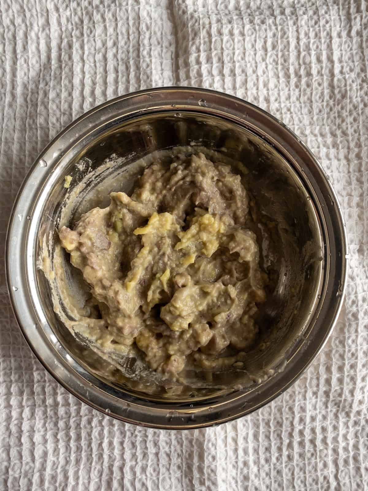 Mashed avocado with a soft, slightly chunky texture in a steel mixing bowl.