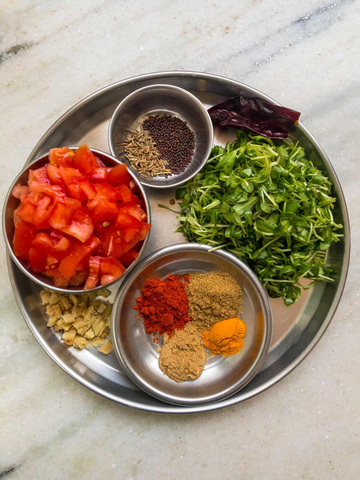 Ingredients for methi toor dal, including chopped tomatoes, fresh fenugreek leaves, ginger, mustard and cumin seeds, dried red chili, and ground spices.