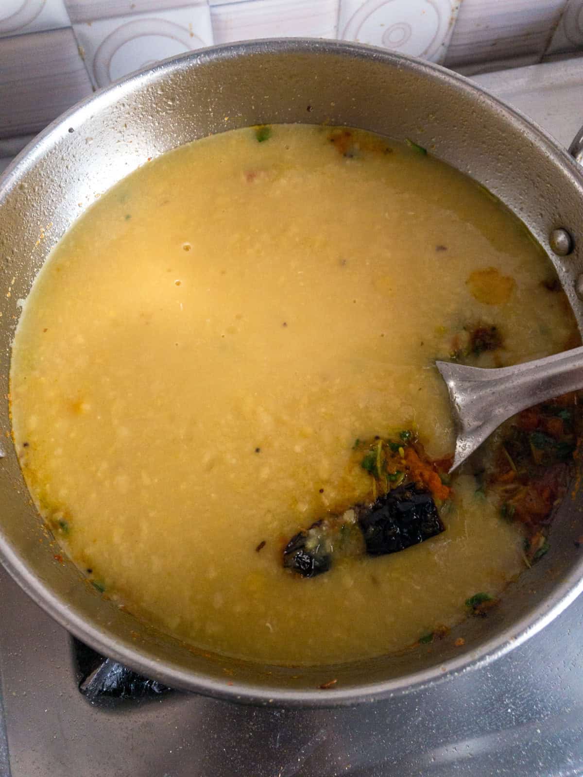Soft cooked toor dal added to the prepared fenugreek and tomato masala in a pan.