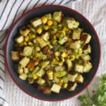 Overhead serving of corn paneer chaat salad with seared paneer cubes, corn, cucumber, tomato, onion, and fresh coriander.