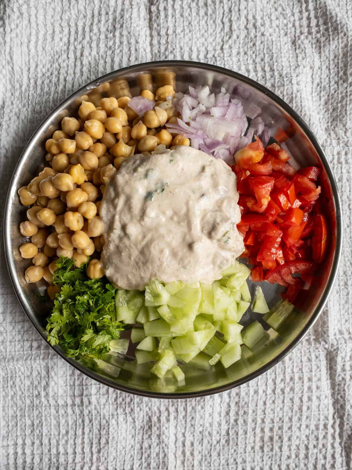 Thick avocado yogurt dressing spooned over chickpeas, cucumber, tomato, onion, and coriander.