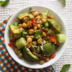 Close overhead view of Indian avocado chickpea salad with creamy avocado, chickpeas, cucumber, tomato, onion, and coriander.