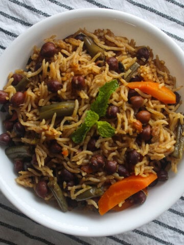 Finished kala chana pulao served with basmati rice, black chickpeas, carrots, green beans, and mint.