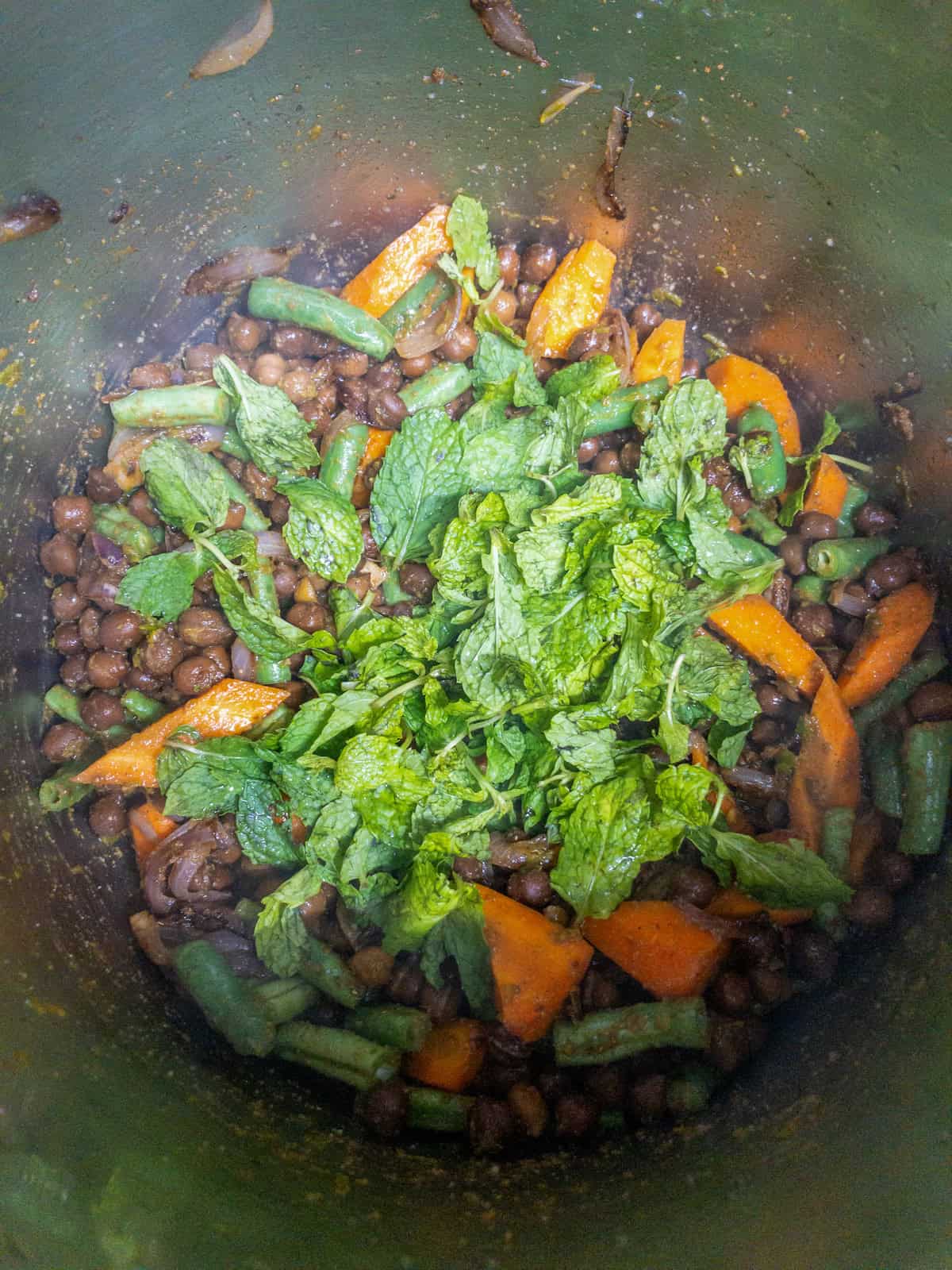 Fresh mint leaves added over seasoned black chickpeas, carrots, and green beans.