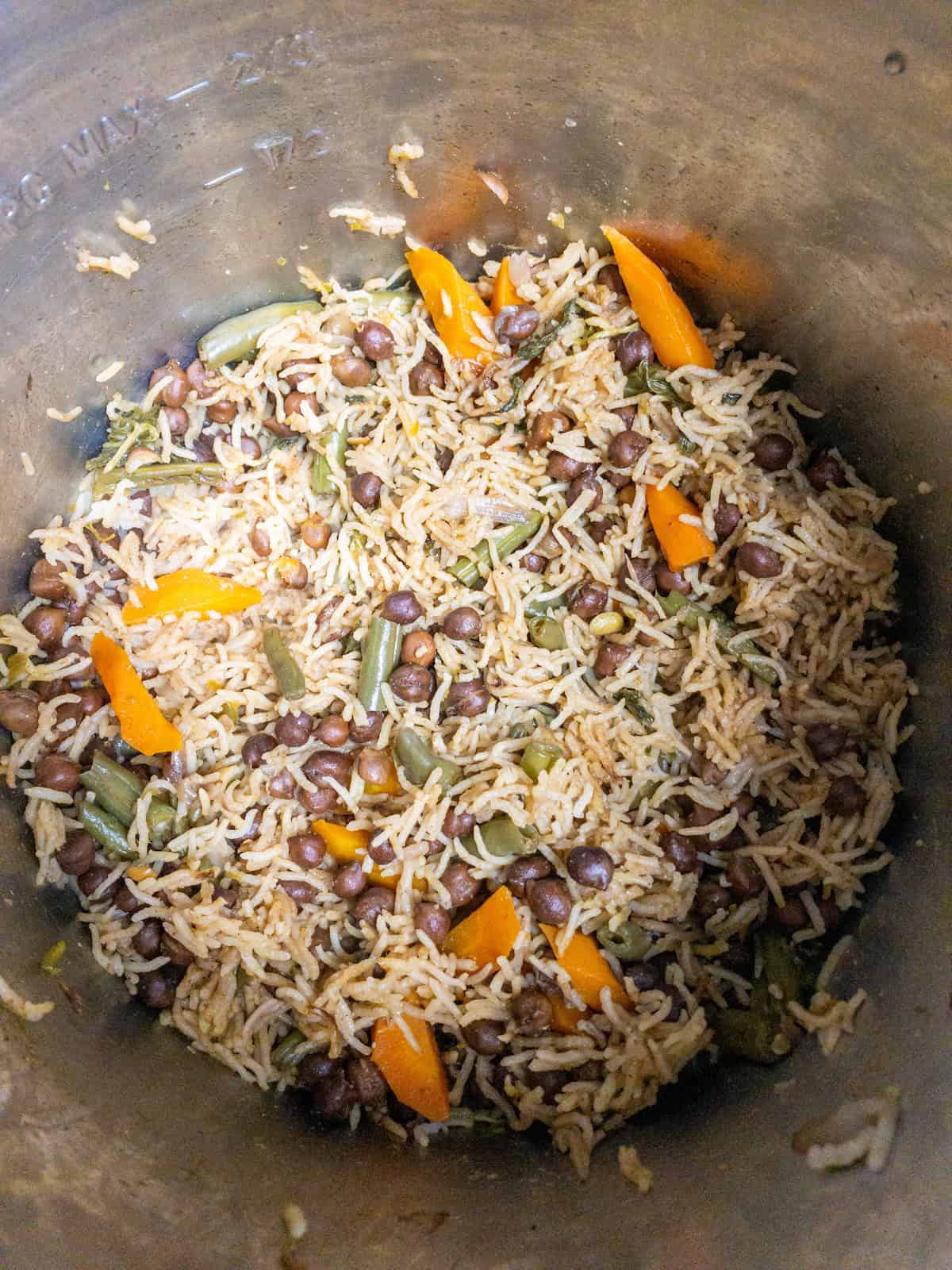 Cooked kala chana pulao with basmati rice, black chickpeas, carrots, and green beans in the pot.
