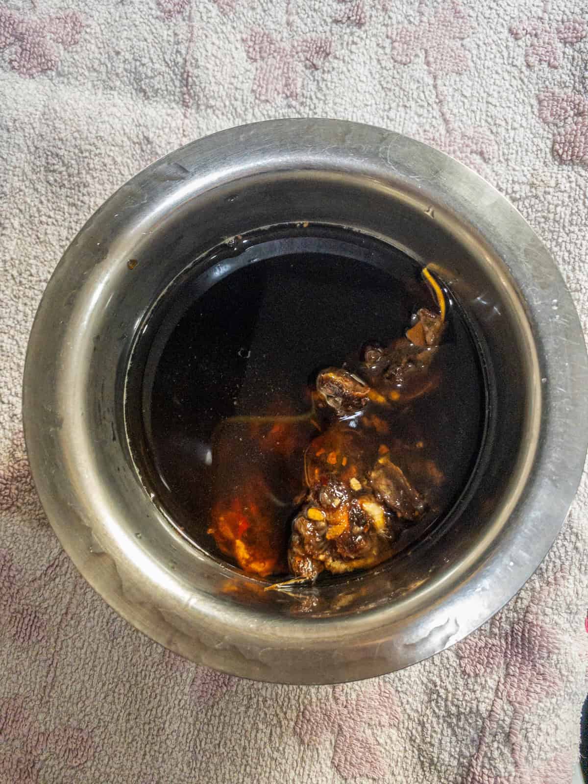 Tamarind pieces soaking in water in a stainless steel bowl until softened.