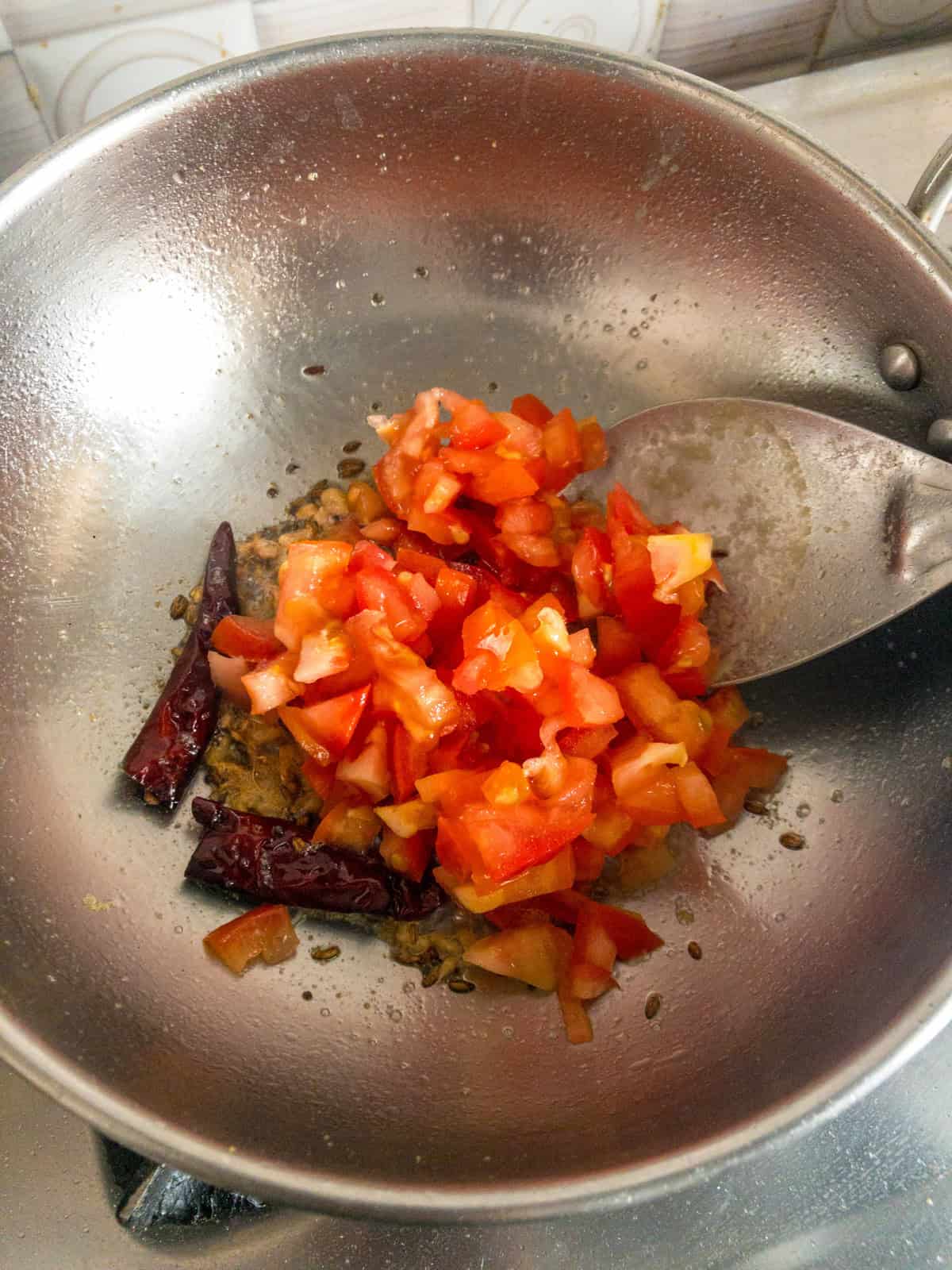 Chopped tomatoes added to a tadka with cumin seeds, dried red chili, and ginger.